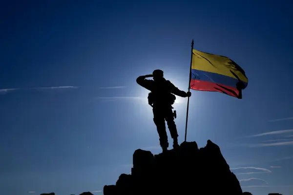 Soldado alzando la bandera colombiana en la noche